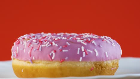 cerca jugoso apetitoso dulce rosado rosado gira sobre un fondo naranja brillante. postre dulce listo para comer. dulces y pasteles tema. rosquilla en esmaltado en un plato. enfoque selectivo