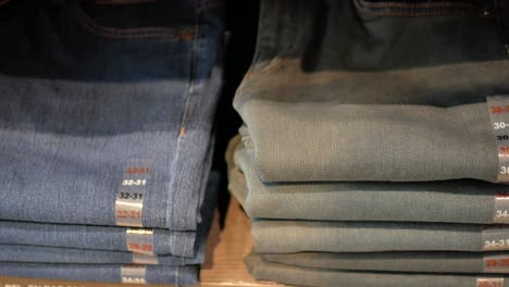 folded blue jeans stacked on shelves in a retail store