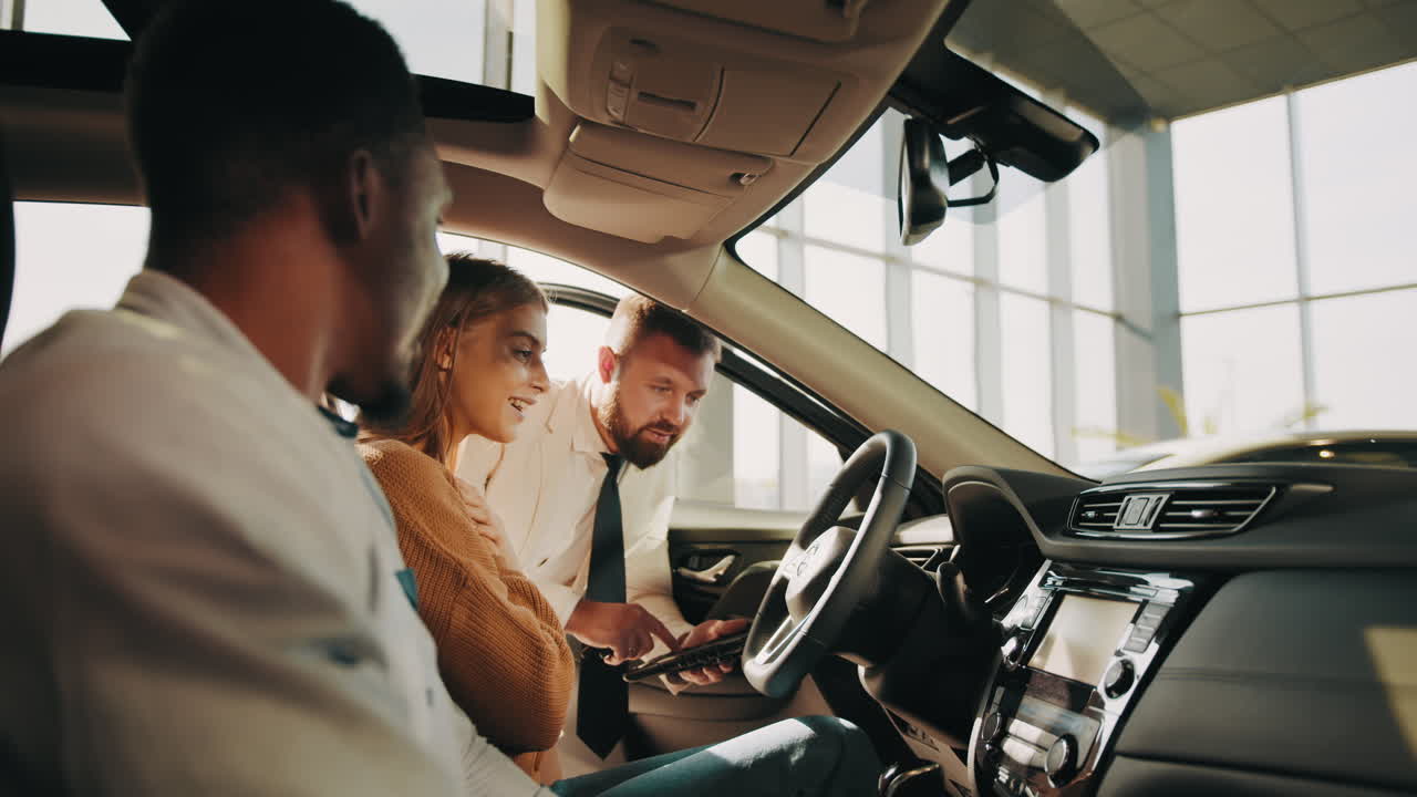 una pareja mirando un coche en una sala de exposiciones con un vendedor