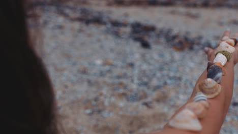 close up woman balancing beautiful seashells on arm enjoying summer vacation