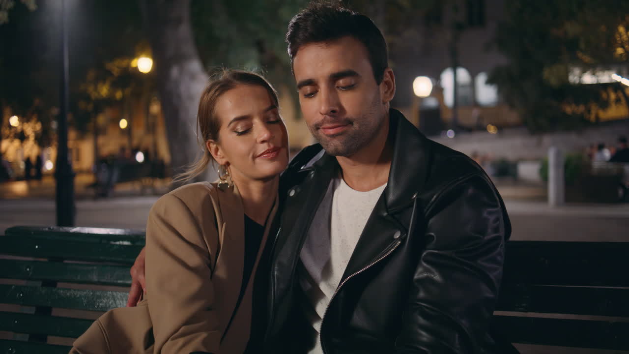 Gros plan sur un homme romantique embrassant la main de sa partenaire lors d'un rendez-vous. Charmant couple se reposant dans un parc en soirée.