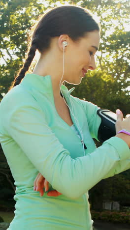 woman adjusting music settings on armband from smartphone