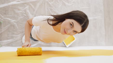 woman painting a wall yellow