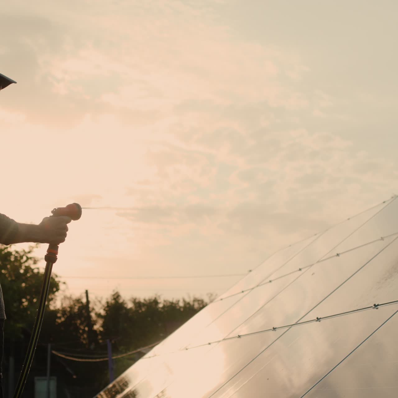 силуэт мужчины, моющего панель солнечной батареи