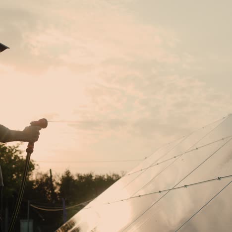 silueta de un hombre lavando un panel de energía solar