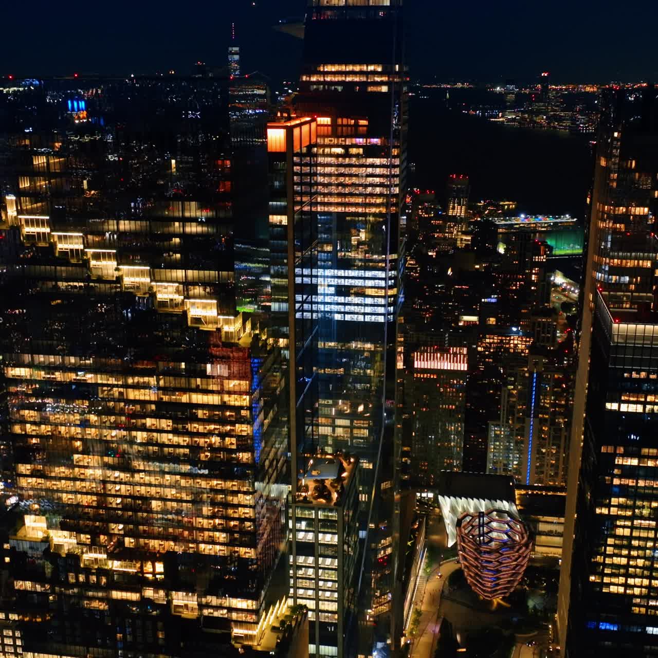Light in the windows of beautiful skyscrapers at night. Drone footage descending above the sparkling cityscape