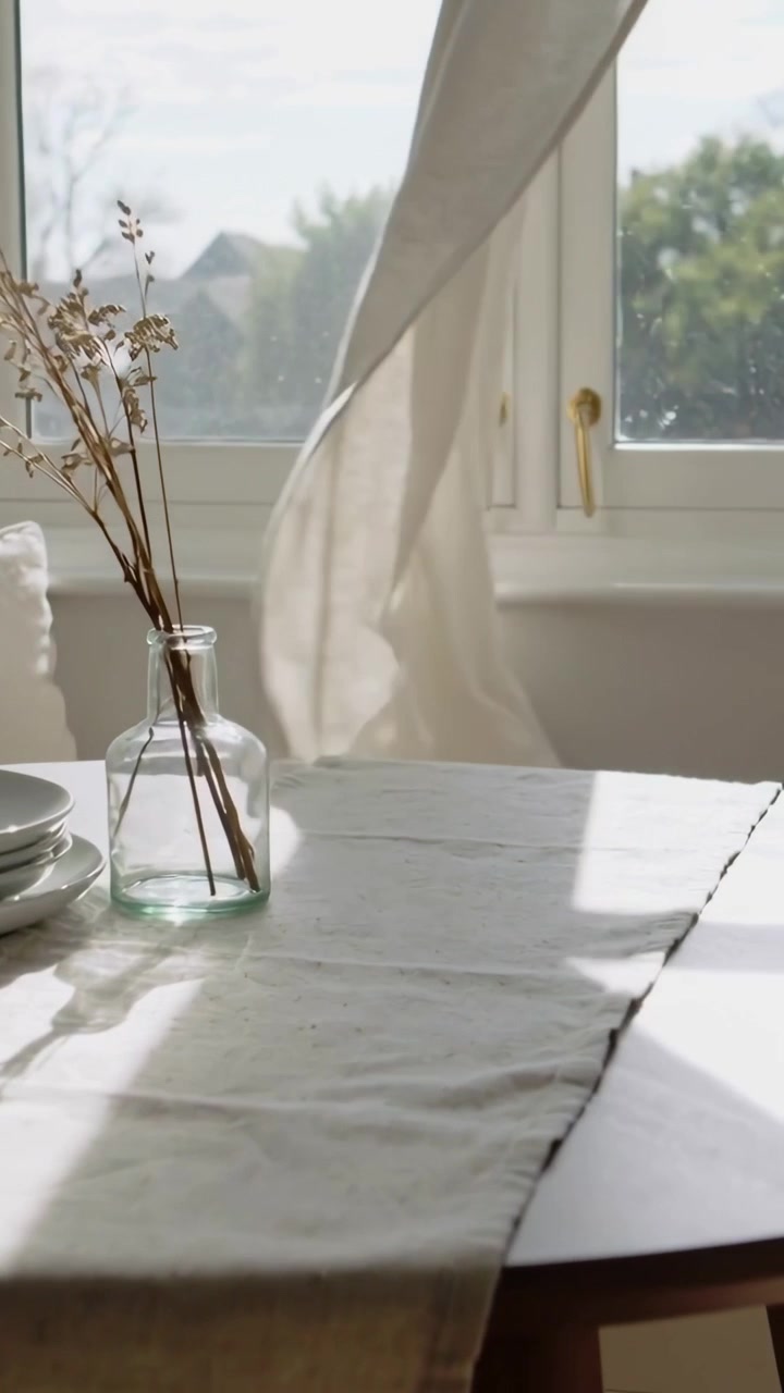 Vertical video: Wind sending curtain swaying across window in home, muting shadows on vase, plates