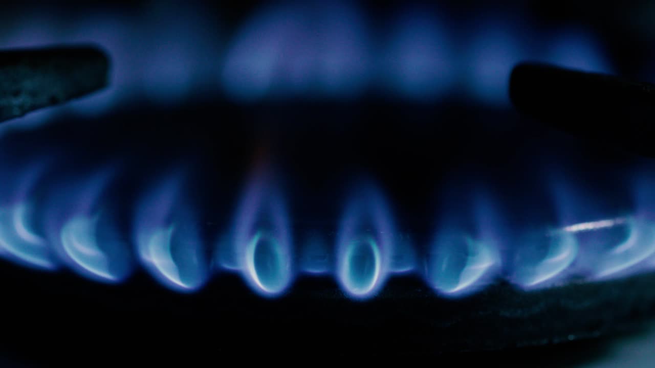 오래된 전통적인 가스 스토브를 비추는 불타는 매치를 가진 세부 사항.