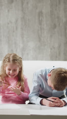 positive african-american native speaking english man teacher talks to little schoolchildren siblings laughing on sofa at home lesson slow motion