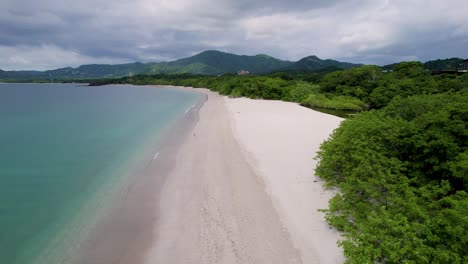 A-low-flying-4K-drone-shot-of-Playa-Conchal,-or-“Shell-Beach”,-and-Puerto-Viejo,-next-to-the-Mirador-Conchal-Peninsula,-along-the-north-western-coast-of-Costa-Rica