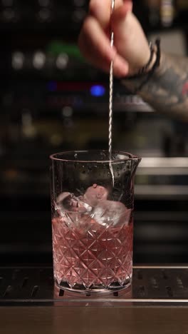 bartender mixing a pink cocktail