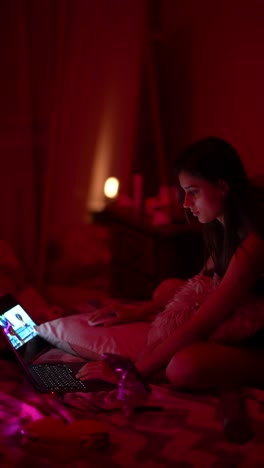 young woman watching movie in bed at night