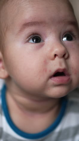 sweet little boy staying on bed and looking up with interest. healthy beautiful child close up. blurred background. vertical video