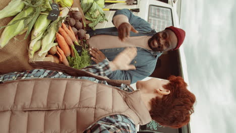 joyous farmers chatting on video call at vegetable market