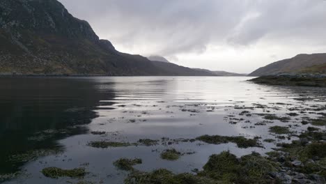 Regen-Fällt-Sanft-Auf-Die-Oberfläche-Eines-Meereslochs-In-Schottland,-Während-Wellen-Langsam-Eine-Felsige-Küste-Und-Mit-Algen-Bedeckte-Felsen-Umspülen