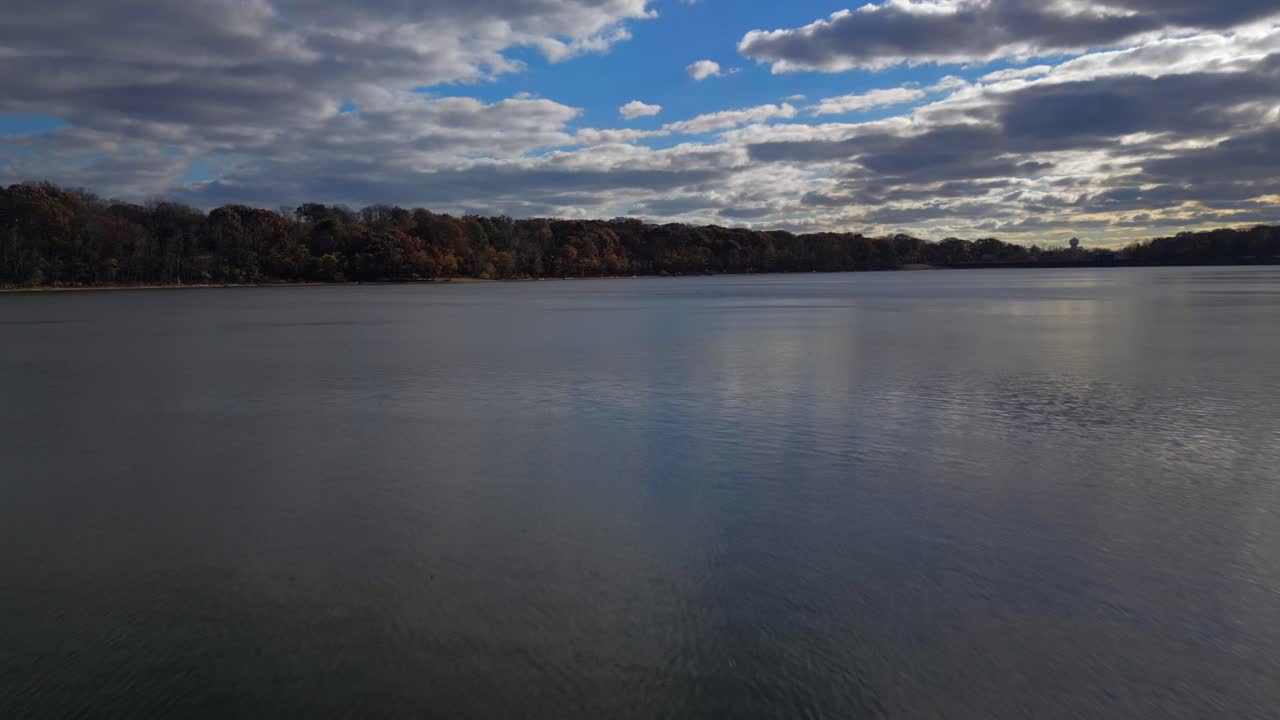 una vista de ángulo bajo sobre un lago tranquilo, justo antes de una puesta de sol nublada