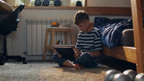 boy using a tablet in his bedroom
