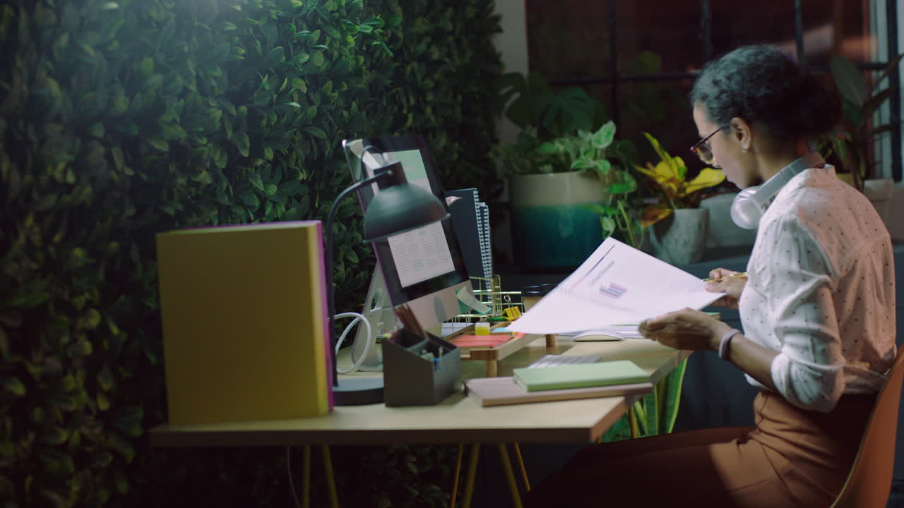 business woman working late writing notes using computer online research information data planning project deadline strategy in office at night