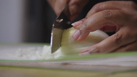 chopping onions on a cutting mat - isolated close up with african american hands