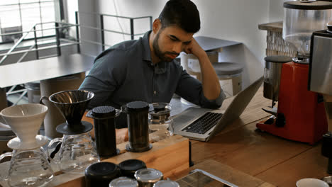 male business executive using laptop while having coffee