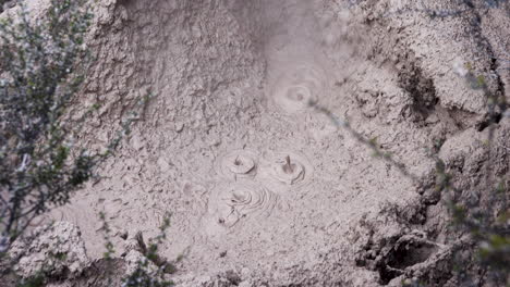 captura de pantalla de una piscina de barro caliente hirviendo o una olla de barro durante el día - fuente termal ácida o fumarola, con agua limitada - el ácido y los microorganismos descomponen la roca circundante en arcilla y barro