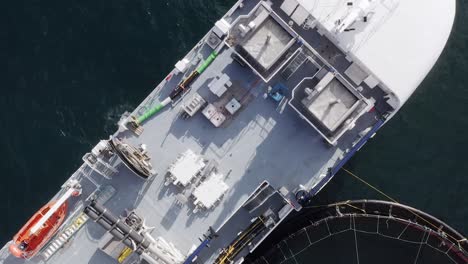 dynamic, bird's eye view drone shot of a fishing well-boat on a fish farm