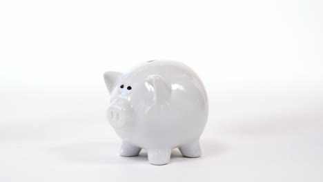 Hand-inserting-coin-in-piggy-bank