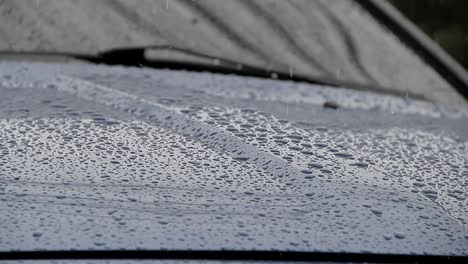 Lluvia-Cayendo-Sobre-El-Capó-De-Un-Auto-Azul,-Auto-Húmedo,-Clima-Lluvioso-Y-Frío