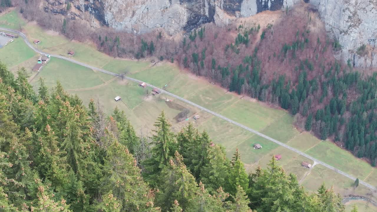 vista lejana de un helicóptero de rescate volando a través del verde valle montañoso de suiza