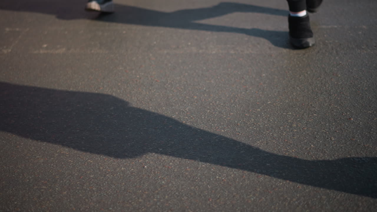 low street view of pedestrian crossing with worn white stripes as people walk past crosswalk, winter city traffic nearby, boots stepping over zebra lines, gritty asphalt texture under bright daylight