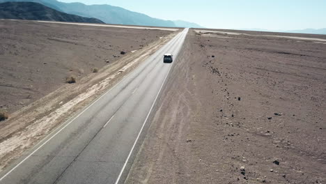 Toma-Aérea-De-Un-Automóvil-Conduciendo-Por-Una-Carretera-De-Aguas-Malas-En-El-Valle-De-La-Muerte,-Un-Paisaje-Impresionante