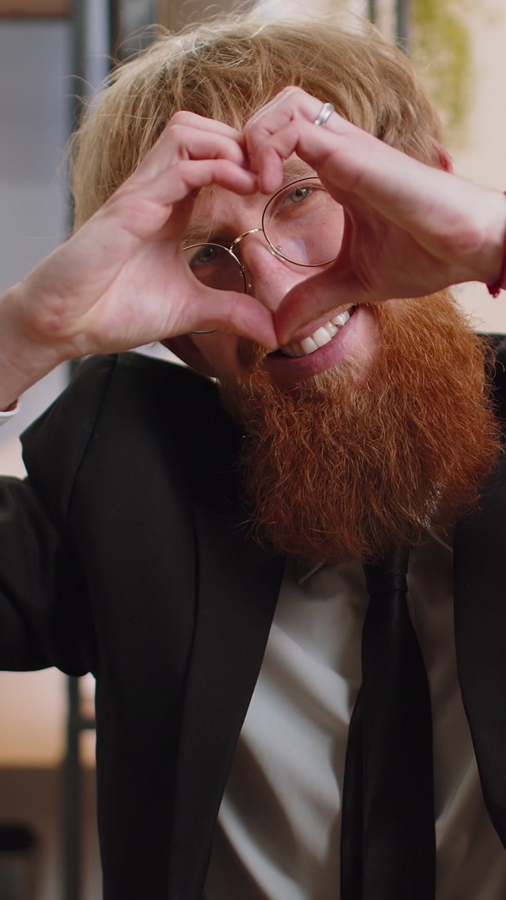 Young business man makes symbol of love showing heart sign to camera express romantic feelings