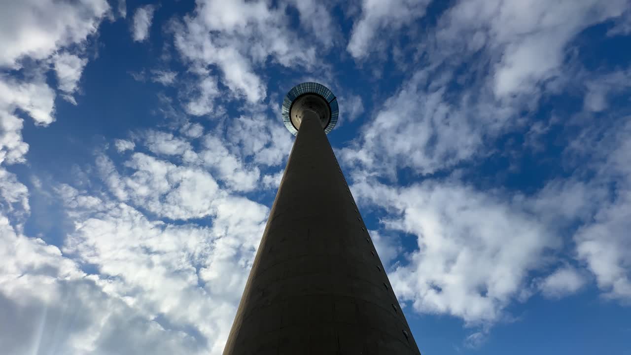 Dramatic low angle shot of the Rheinturm in Düsseldorf with blue sky and clouds