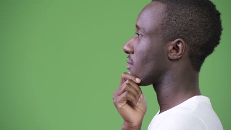 profile view of young african man thinking against green background