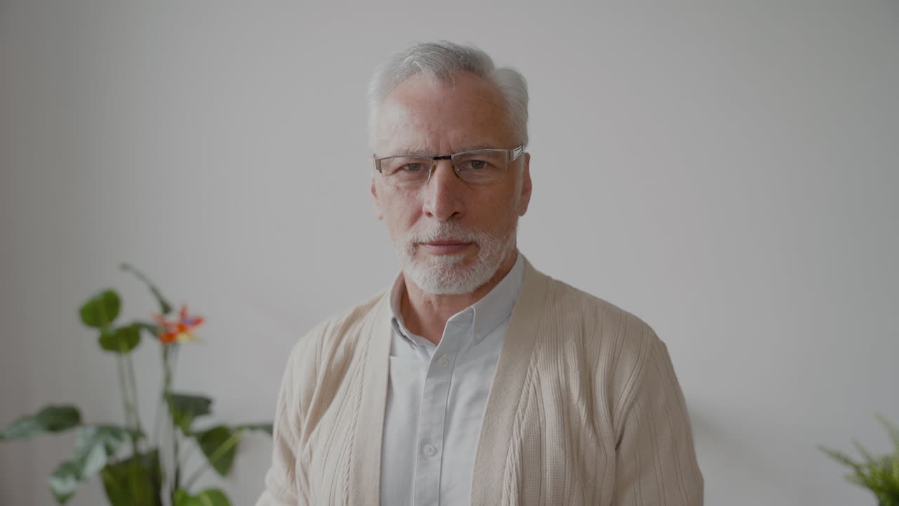 hombre mayor mirando serio a la cámara mientras se quita los anteojos