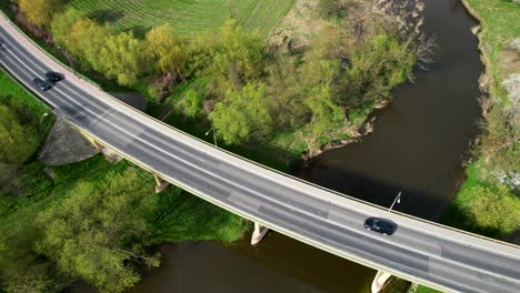 drone shot old bridge in łęczna, poland, cars driving, camera tilting down, river, and nature