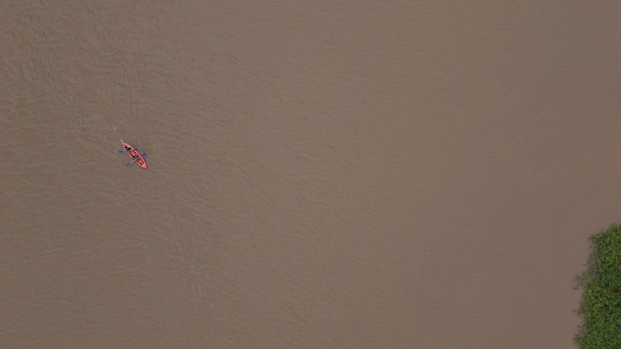 Top-down drone footage of kayakers on the vast, murky Amazon River waters