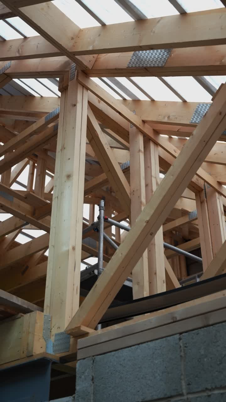 Wooden beams form a complex roof structure of a house under construction