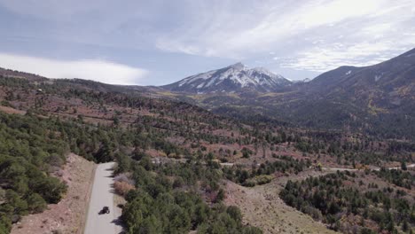 Aérea:-Vehículo-Todo-Terreno-En-La-Carretera-Del-Valle-Cerca-De-Moab-Utah,-Lejanas-Montañas-De-La-Sal