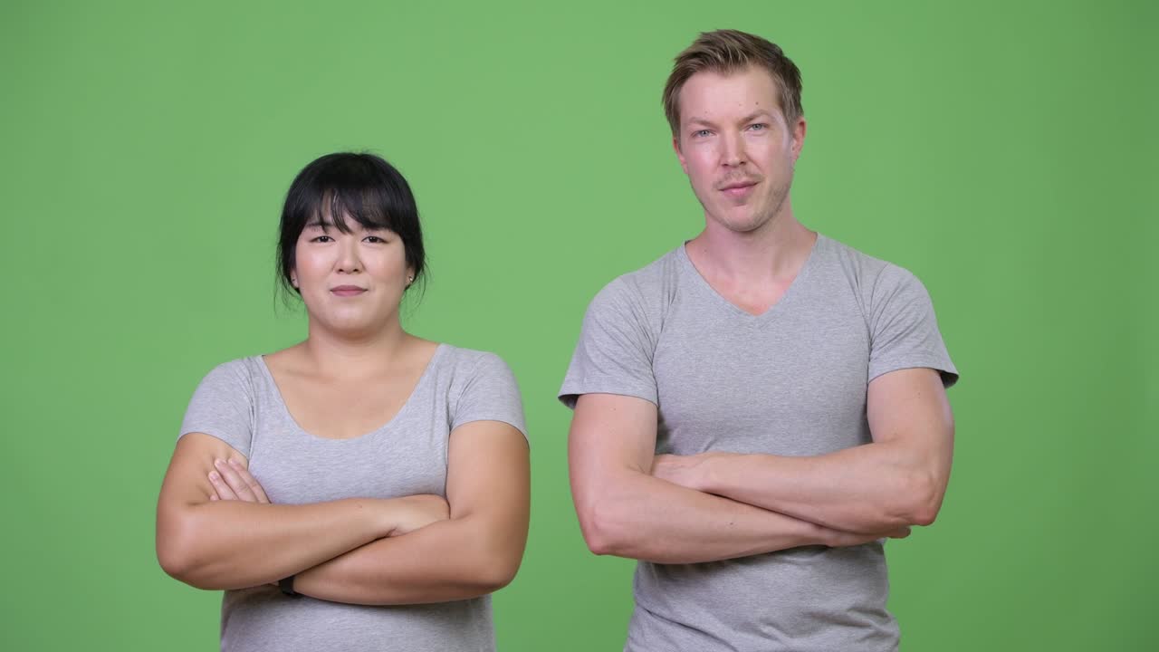 Happy young multi-ethnic couple with arms crossed together