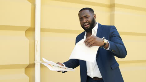 Upset-businessman-checking-documents-outside.-Afro-man-finding-mistake-in-papers