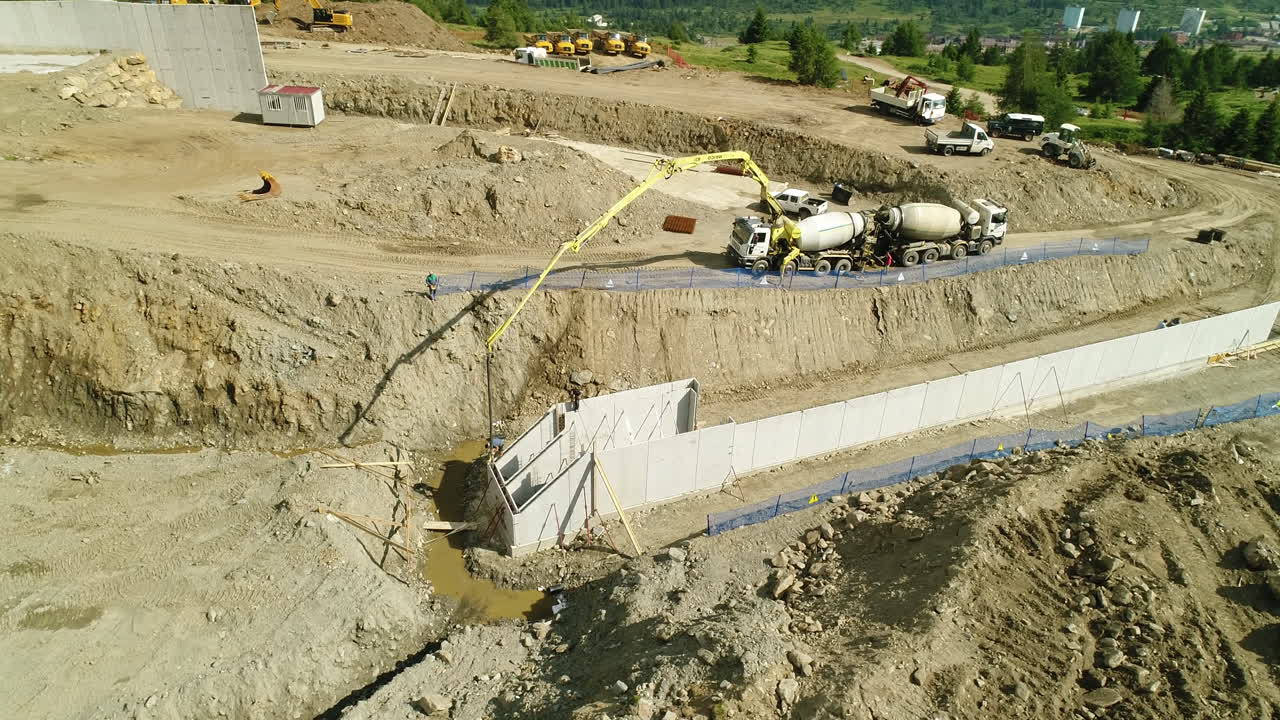 tomada aérea de drones de maquinaria pesada trabajando en un sitio de construcción de presa en las montañas