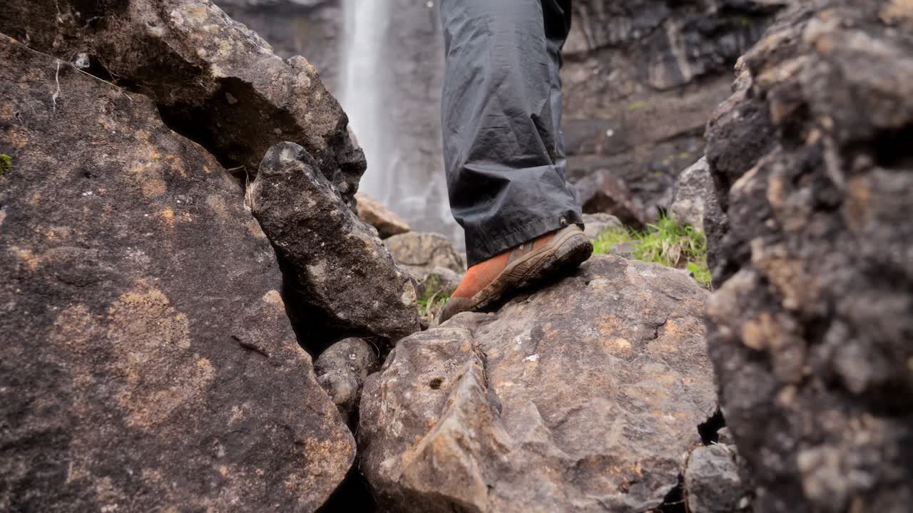 A person hiking on rocky terrain with focus on boots and rugged outdoor surroundings