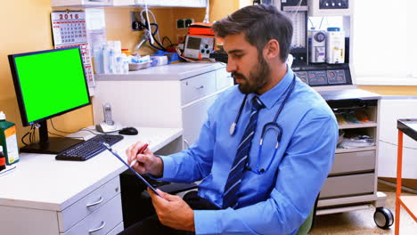 Doctor escribiendo en un portapapeles