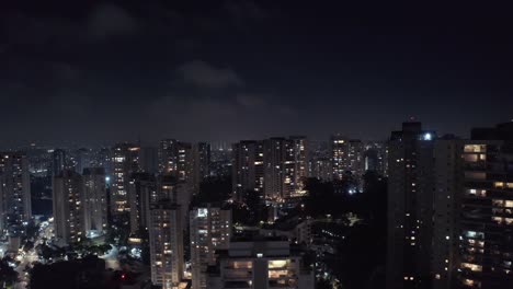Descending-Sao-Paulo-Morumbi-neighborhood-lit-up-at-night-with-downtown-cityscape-skyline,-Aerial-Brasil