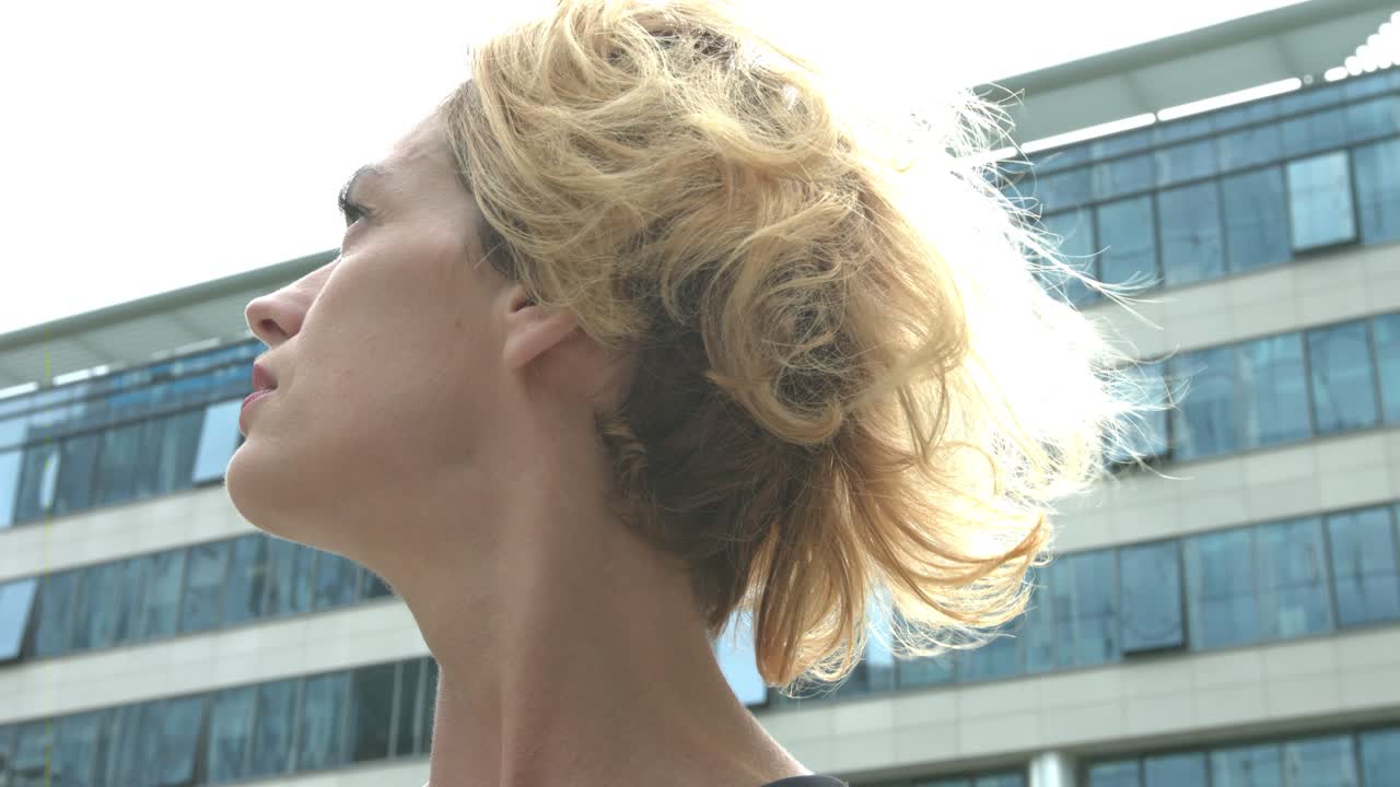 A young business woman  looking around the office buildings surrounding her. concept of looking for a job and the first day at work