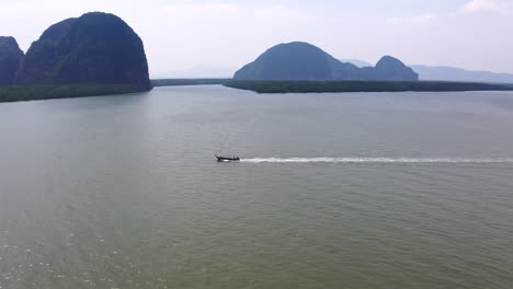 Long-tail-boat-cruising-in-coastal-sea-waters-with-islands-in-Thailand