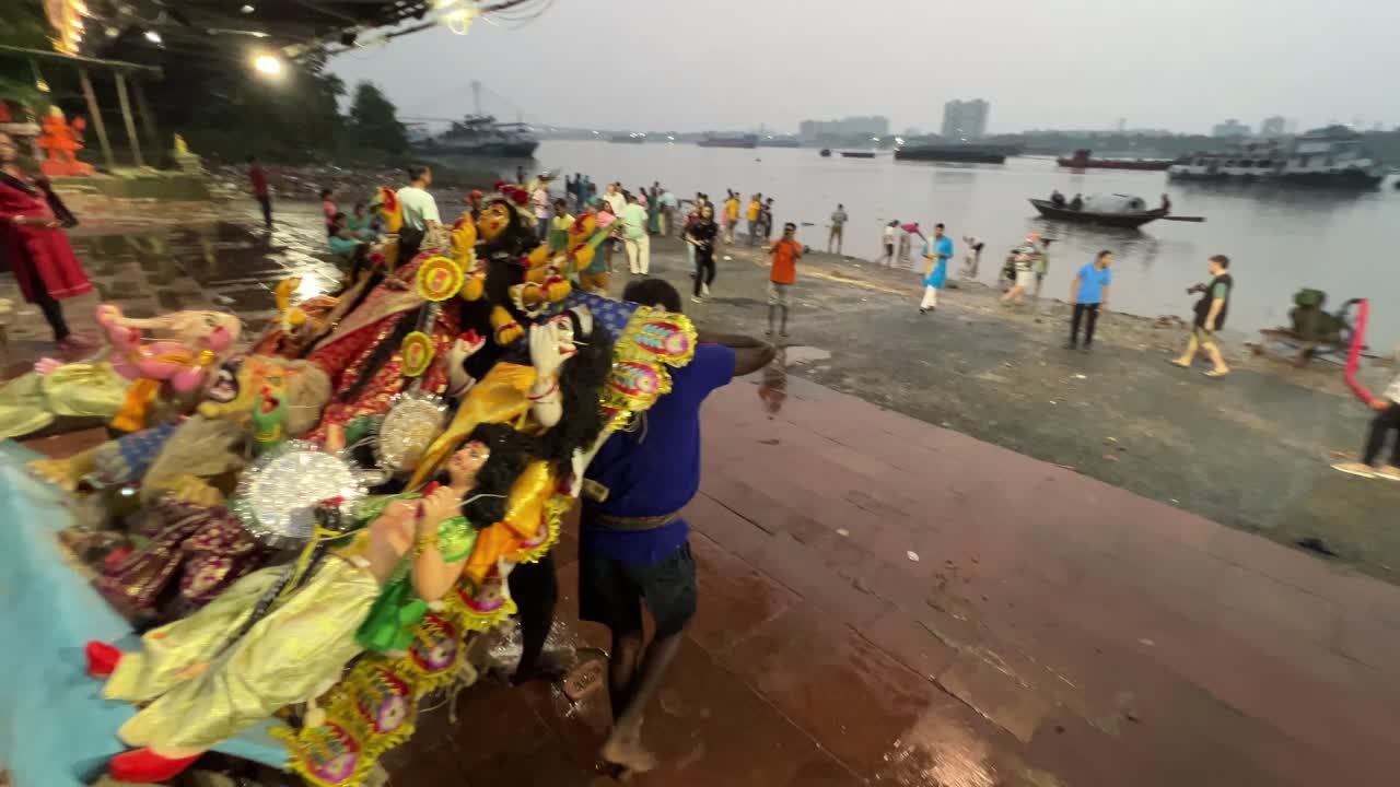 Goddess Durga idol moving forward towards Ganga river by group of men for immersion of idol into river during evening in Kolkata, India. Navratri.