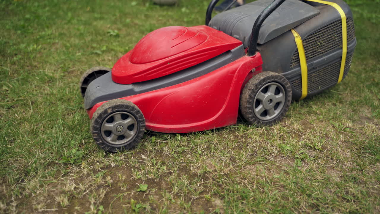 Lawn mower cutting the grass. Gardening activity. Cutting grass in the garden. Gardener working with mower machine in the garden.