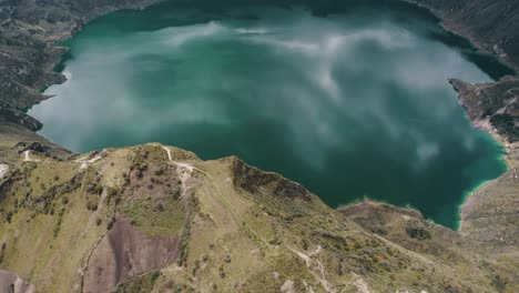 Aerial-top-down-view-of-trail-on-mountain-peak-and-idyllic-crater-lake-in-the-valley-after-eruption